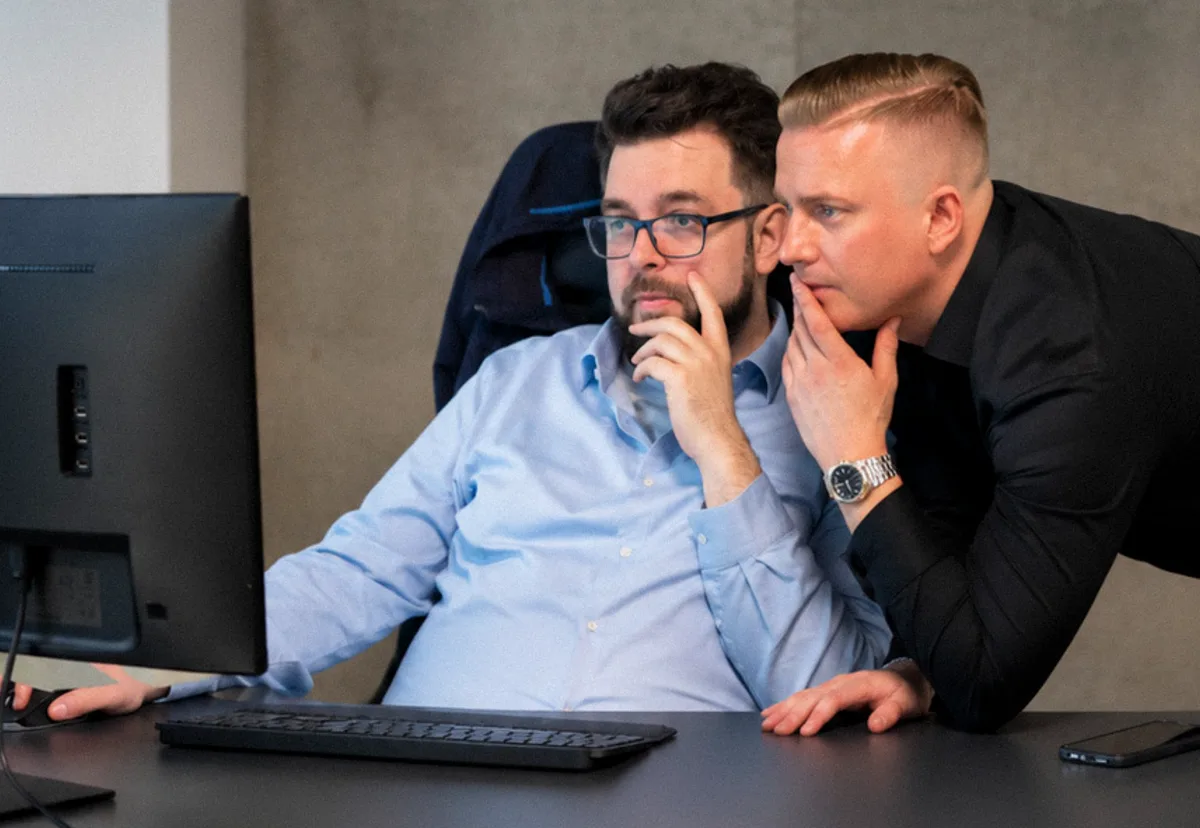 To forretningspartnere håndhilser over et møtebord i et lyst kontor